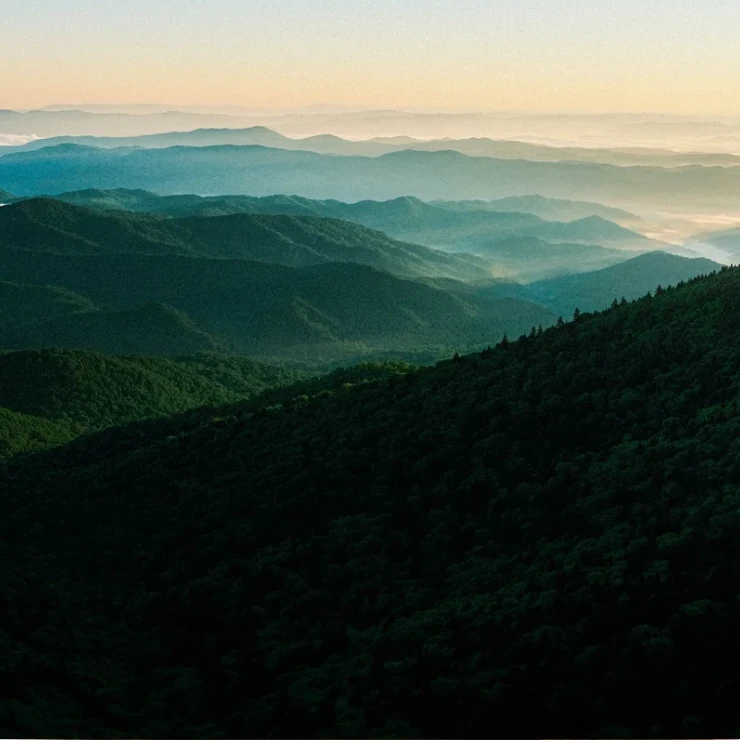 Layered green mountain ridges fading into the morning haze.